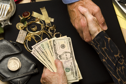 Two shaking hands, exchanging money and jewelry - pawn shop services